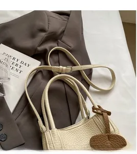 Close-up of beige lychee texture bucket bag with adjustable strap and decorative charm