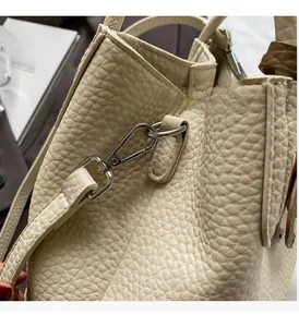 Close-up of creamy white lychee grain leather bag with polished silver metal hardware