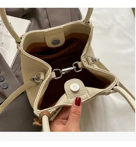 Detail of off-white lychee leather bucket bag showing silver hook and magnetic closure