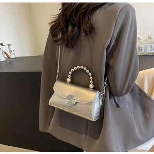Détails d'un sac à main argenté avec poignée en perles et boucle à tourbillon