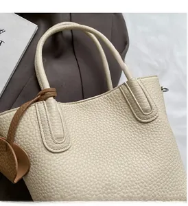 Detail of cream white leather bucket bag showing lychee grain texture and dual handles