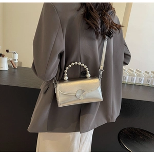 Détail du mini sac argenté avec poignée en perles et fermoir métallique chic
