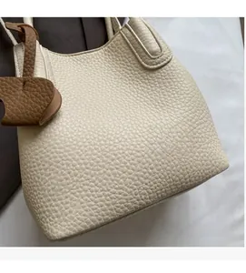 Detail of off-white lychee grain leather handbag with brown heart-shaped pendant