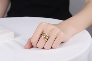 Detailed close-up of a gold-plated hugging hands ring on a model hand with polished finish