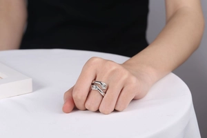 Detail shot of adjustable silver embrace ring showing hands hug design on finger