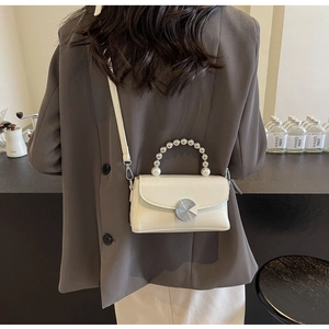 Détail du sac à main crème gaufré crocodile avec poignée en perles et fermoir métal