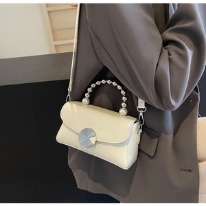Détail du mini sac crème effet croco avec poignée élégante en perles et argent