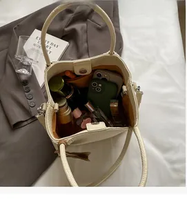 Overhead view showing spacious interior of the cream leather bucket bag with daily items