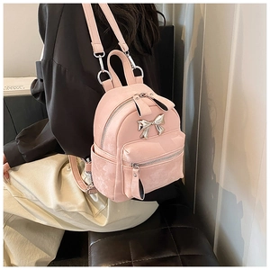 Detail of pink faux leather mini backpack featuring silver bow decoration and adjustable straps