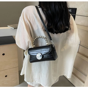 Détails du sac noir motif crocodile avec boucle métallique et anse perlée