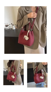 Detail view of burgundy pebble leather bucket bag with cute white elephant charm