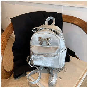 Detailed shot of silver metallic mini backpack with aesthetic 3D bow decoration on wooden chair