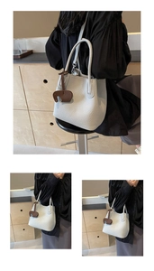 Detail of grey pebbled leather bucket bag with brown elephant charm and long handle