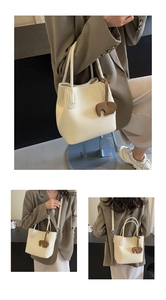 Detail of cream lychee leather bucket bag with brown elephant charm and adjustable strap