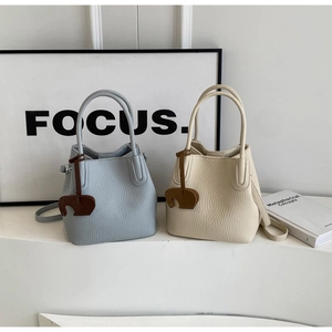 Detail view of lychee texture bucket bags in light blue and beige with elephant charms