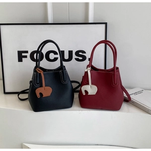 Close-up of pebble grain leather buckets bags in black and wine red with elephant charm