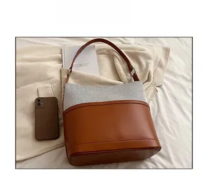 Detailed comparison showing large bucket shoulder bag capacity next to a smartphone