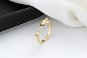 Macro detail of golden shark open ring featuring a blue gemstone eye and polished finish
