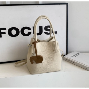 Detail of cream white lychee pattern leather bucket bag with cute elephant charm