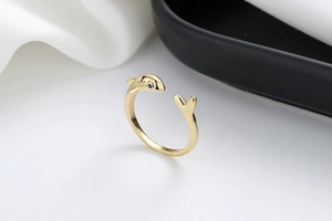 Close-up of golden shark-shaped open ring with a blue gemstone eye and polished finish