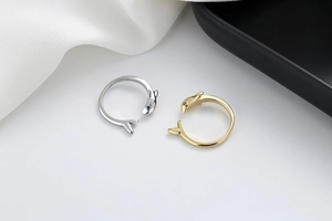 Detailed view of shark open rings in gold and silver with blue gemstone eyes