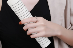 Close-up of a silver dolphin open ring with blue eye detail worn on a finger