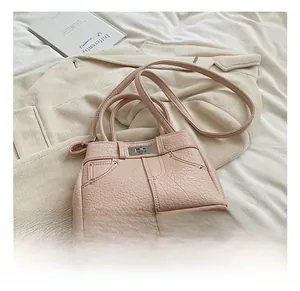 Detail of pink faux leather handbag with lychee texture and denim jacket design elements