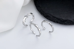 Detailed view of three silver rings with irregular wave textures on silk and rock