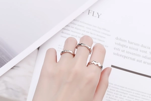 Detailed close-up of layered minimalist silver wavy rings with lava texture on fingers