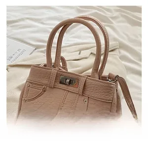 Detail of light pink lychee textured handbag with metal turn-lock and rivet decorations