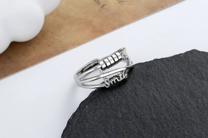 Close-up of silver smile ring with four rotating beads for stress relief on stone