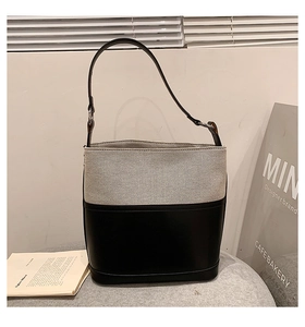 Detail of minimalist bucket bag featuring premium black leather and beige canvas textures