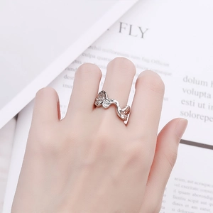 Minimalist silver irregular wave ring with sparkling zircons worn on hand over a magazine