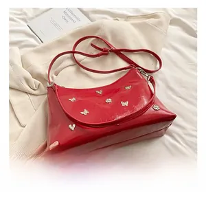 Détail du sac cabas rouge brillant avec ornements papillon et cœur en métal