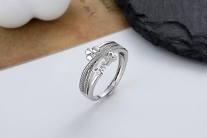 Detail of adjustable silver ring with 'Smile' text, clover icon and paved zircon stones