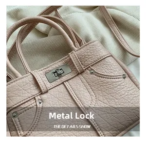 Close-up of pink litchi pattern handbag featuring a silver hardware lock and metal rivets