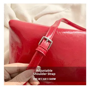 Bandoulière réglable en cuir verni rouge avec détail de boucle argentée sur sac