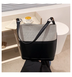 Detail of minimalist bucket bag showing canvas texture and black leather splicing