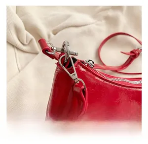 Détail d'un sac à main en cuir verni rouge avec boucle papillon argentée et crochet