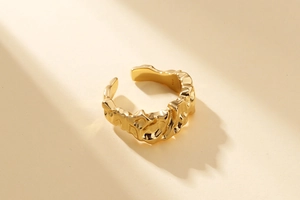 Détail de la texture dorée plissée irrégulière sur cette bague réglable moderne