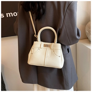 Chic cream leather handbag with denim pocket detail shown worn with a charcoal blazer