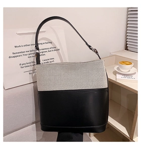 Detail of a two-tone bucket bag featuring beige canvas weaving and a black leather base