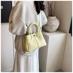Detail of light yellow lychee grain leather handbag with silver rivets and metal lock