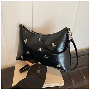 Détail du sac en similicuir noir avec rivets papillon argentés et texture huilée