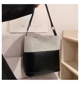 Detailed close-up of the two-tone bucket bag featuring canvas and black leather finish