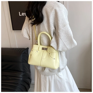 Detail of light yellow leather handbag with denim style stitching and metal twist lock
