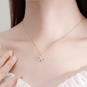 Rotating windmill pendant necklace in gold finish worn on a female collarbone