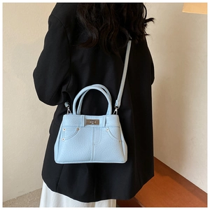 Chic light blue leather handbag shown on model with metal turn-lock and contrast stitching