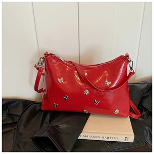 Vue détaillée du sac en cuir verni rouge avec ornements papillons 3D et fermeture éclair