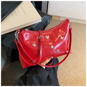 Détail du sac cabas rouge brillant avec clous papillon argentés et boucles métalliques